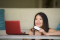 Lifestyle portrait of young beautiful and happy Asian Chinese woman holding credit card banking and online shopping with laptop co Royalty Free Stock Photo