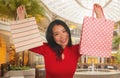 Lifestyle portrait of young beautiful and happy Asian Chinese woman holding shopping bags at modern shopping mall smiling excited Royalty Free Stock Photo