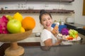 Lifestyle portrait of young beautiful and happy Asian Chinese woman at home kitchen relaxed preparing vegetables salad smiling Royalty Free Stock Photo