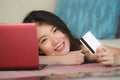 Lifestyle portrait of young beautiful and happy Asian Korean woman holding credit card banking and online shopping with laptop com Royalty Free Stock Photo