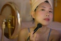 Lifestyle portrait of young beautiful and happy Asian woman applying makeup and beauty facial treatment looking in mirror at home Royalty Free Stock Photo