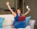 Lifestyle portrait of young beautiful and happy girl at home living room holding credit card using laptop computer for banking an Royalty Free Stock Photo