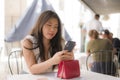 Lifestyle portrait of young beautiful and sweet Asian Japanese woman sitting happy outdoors at street cafe using internet travel Royalty Free Stock Photo