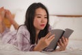 Young beautiful and sweet Asian Korean woman in bed reading book novel feeling happy and playful or studying at home wearing cute Royalty Free Stock Photo