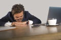 Lifestyle portrait of young exhausted and sleepy business man feeling wasted and hangover working lazy on Monday at computer desk