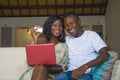 Lifestyle portrait of young happy and attractive black afro American couple enjoying at home using credit card and laptop computer Royalty Free Stock Photo