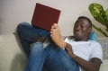 Young happy and attractive black afro American man using credit card and laptop computer relaxed and cheerful at living room sofa Royalty Free Stock Photo