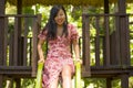 Lifestyle portrait of young happy and beautiful Asian Chinese woman in sweet Summer dress playing on slide at city park smiling Royalty Free Stock Photo