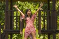 Lifestyle portrait of young happy and beautiful Asian Chinese woman in sweet Summer dress playing on slide at city park smiling Royalty Free Stock Photo