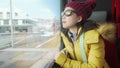 Lifestyle portrait of young happy and beautiful Asian Chinese woman in yellow jacket and hat looking through train window Royalty Free Stock Photo