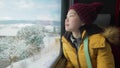 Lifestyle portrait of young happy and beautiful Asian Chinese woman in yellow jacket and hat looking through train window Royalty Free Stock Photo