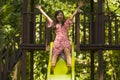 Lifestyle portrait of young happy and beautiful Asian Korean woman in sweet Summer dress playing on slide at city park smiling Royalty Free Stock Photo