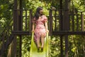 Lifestyle portrait of young happy and beautiful Asian Korean woman in sweet Summer dress playing on slide at city park smiling Royalty Free Stock Photo