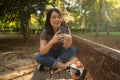 Lifestyle portrait of young happy and beautiful Asian Korean woman using internet app on mobile phone relaxed and cheerful at city Royalty Free Stock Photo