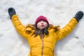 Lifestyle portrait of young happy and beautiful Asian Korean woman in yellow winter jacket and hat playing excited lying on snow Royalty Free Stock Photo