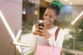 Young happy and beautiful black African American woman holding shopping bags and mobile phone buying at mall fashion store smiling Royalty Free Stock Photo