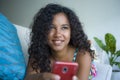 Lifestyle portrait of young happy and beautiful black african american woman at home using mobile phone networking and te Royalty Free Stock Photo