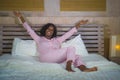 Lifestyle portrait of young happy and beautiful black afro American woman in pajamas lying relaxed and playful on bed smiling Royalty Free Stock Photo