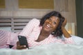 Young happy and beautiful black African American woman in pajamas lying relaxed smiling cheerful and fresh using internet mobile Royalty Free Stock Photo