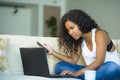 Lifestyle portrait of young happy and beautiful black afro American woman using internet mobile phone while working on laptop com Royalty Free Stock Photo