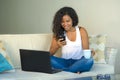Lifestyle portrait of young happy and beautiful black afro American woman using internet texting on mobile phone while working on Royalty Free Stock Photo