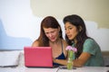 Young happy caucasian woman and beautiful hispanic girl working at office cafe with laptop computer discussing as digital business Royalty Free Stock Photo