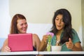 Young happy caucasian woman and beautiful hispanic girl working at office cafe with laptop computer discussing as digital business Royalty Free Stock Photo