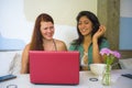 Young happy caucasian woman and beautiful hispanic girl working at office cafe with laptop computer discussing as digital business Royalty Free Stock Photo