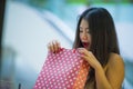 Lifestyle portrait of young happy and excited Asian Chinese woman looking excited into shopping bag buying at mall clothing store Royalty Free Stock Photo