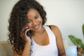 Lifestyle portrait of young happy and gorgeous black African American woman talking on mobile phone at home living room sofa couch Royalty Free Stock Photo
