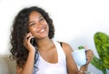 Lifestyle portrait of young happy and gorgeous black latin American woman talking on mobile phone at home living room sofa couch e Royalty Free Stock Photo