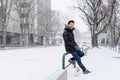 Lifestyle portrait of young man in coat with snowy streets