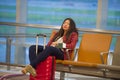 Young pretty tired and exhausted Asian Korean tourist woman in airport sleeping bored sitting at boarding gate hall waiting for de Royalty Free Stock Photo