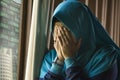 Young sad and depressed Muslim woman in Islam traditional Hijab head scarf at home window feeling unwell suffering depression