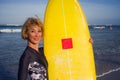 Young beautiful and happy surfer girl holding yellow surf board smiling cheerful enjoying summer holidays in tropical beach w