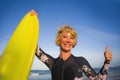 Young beautiful and happy surfer woman holding yellow surf board smiling cheerful enjoying summer holidays in tropical beach Royalty Free Stock Photo