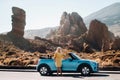 Lifestyle portrait of a young woman enjoying road trip on the desert valley, getting out the convertible car on the roadside Royalty Free Stock Photo