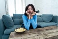 Portrait of a young woman looking scared and shocked watching TV. Human expressions and emotions Royalty Free Stock Photo