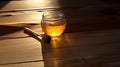 Lifestyle product shot of a full glass of beautiful honey and spindle on a wooden table. Play light and shadow