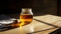 Lifestyle product shot of a glass of honey and spindle illuminated by the sun from the window on a wooden table. Play