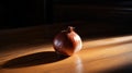 Lifestyle product shot of whole golden onion, illuminated from the side on a wooden table. Play light and shadow