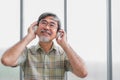 Happy asian senior man wearing eyeglasses and headphone with listening music in living room at his home Royalty Free Stock Photo