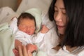 Lifestyle shot of Asian Chinese woman holding adorable newborn baby girl skin on skin  hours after birth laying happy on hospital Royalty Free Stock Photo