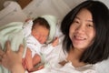 Lifestyle shot of Asian Chinese woman holding adorable newborn baby girl skin on skin  hours after birth laying happy on hospital Royalty Free Stock Photo