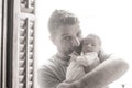 Lifestyle shot in black and white of young and happy man holding tenderly in his arms adorable newborn baby girl  in father and Royalty Free Stock Photo