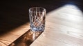 Lifestyle shot of empty glass on a wooden table. Light passes through, play of light and shadow