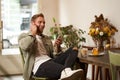 Lifestyle shot of handsome young man, looking at his mobile phone, listening to music in wireless earphones, sitting in Royalty Free Stock Photo