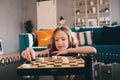 Lifestyle shot of smart kid girl playing checkers at home