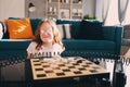 Lifestyle shot of smart kid girl playing checkers at home