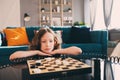 Lifestyle shot of smart kid girl playing checkers at home